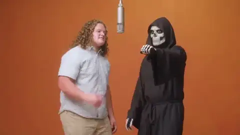 Hotel Lobby AI video of a young man sharing the mic with the Grim Reaper